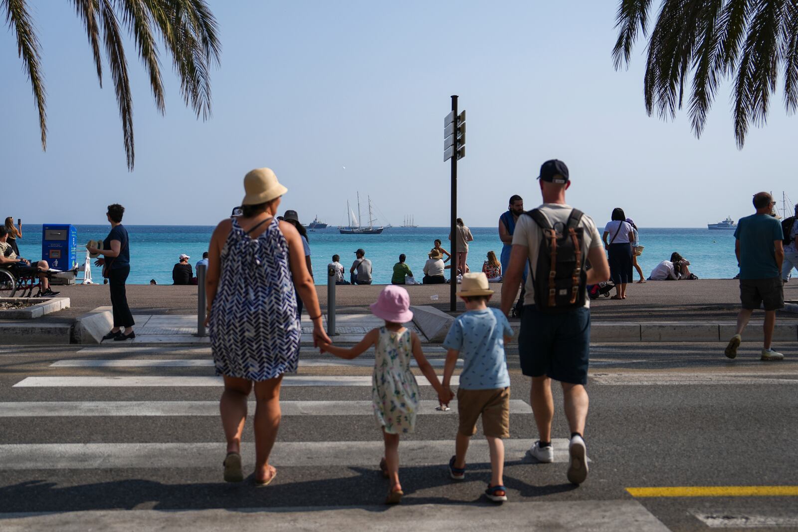 People cross a street as vessels sail during the "Ocean Wonders" event in honor of World Oceans Day ahead of the U.N. Ocean Conference on Sunday, June 8, 2025, in Nice, France. (AP Photo/Annika Hammerschlag)