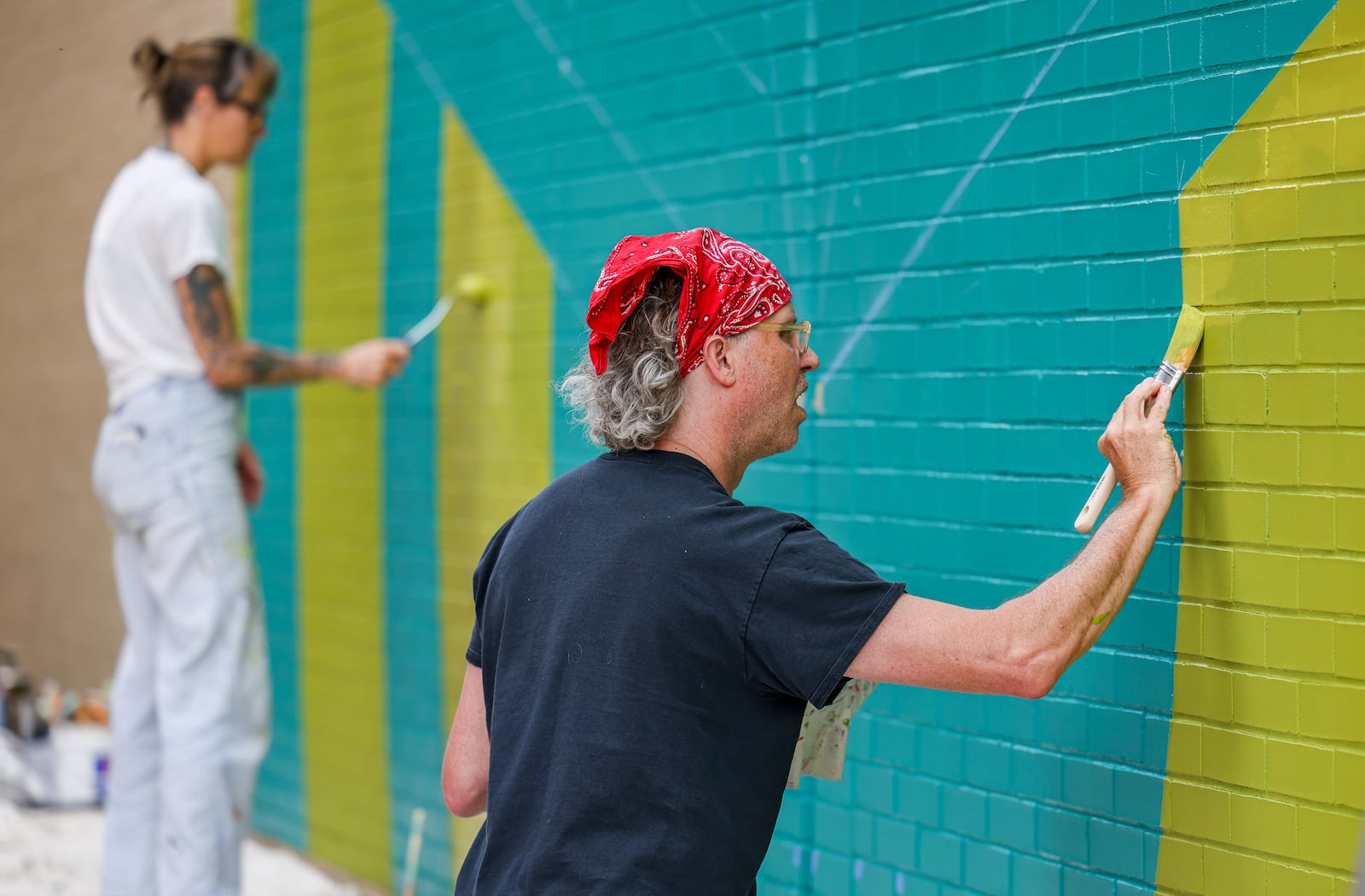 Matt Lynch (right) and Maggie Leadman paint a mural on Courthouse Square on Wednesday, May 14. The mural was designed by Atalie Gagnet, who was overseeing the project and was also painting Wednesday along with Jenny Ustick. The mural was being prepared ahead of the NATO assembly, which is set to occur Memorial Day weekend. BRYANT BILLING / STAFF