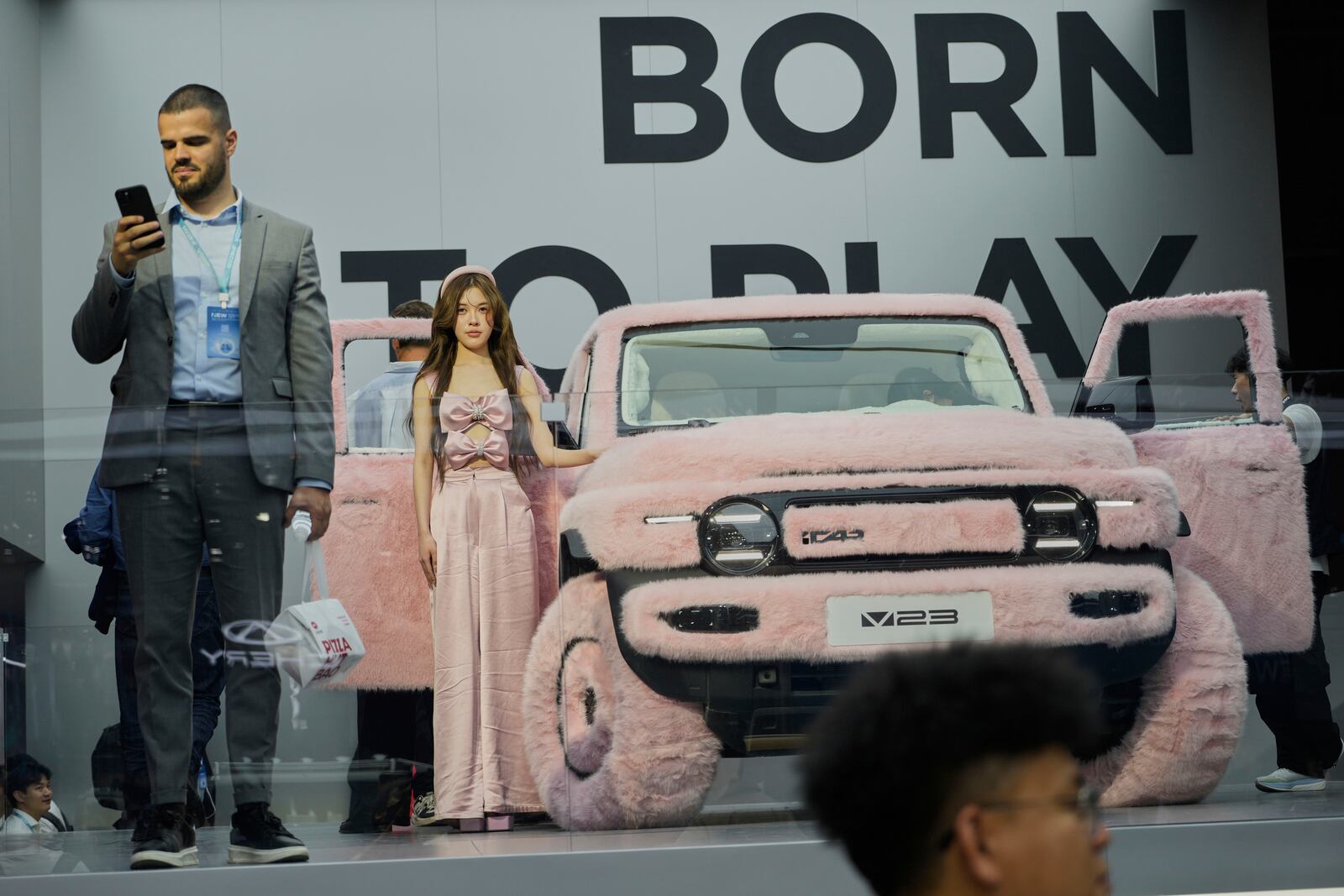 A woman stands next to a iCar 23 decked out with pink fur at the Shanghai auto show on Wednesday, April 23, 2025. (AP Photo/Ng Han Guan)