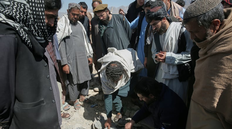 Residents and Taliban police gather the remains of a projectile at the site of a strike in Kabul, Afghanistan, Friday, March 13, 2026. (AP Photo/Barackatullah Popal)