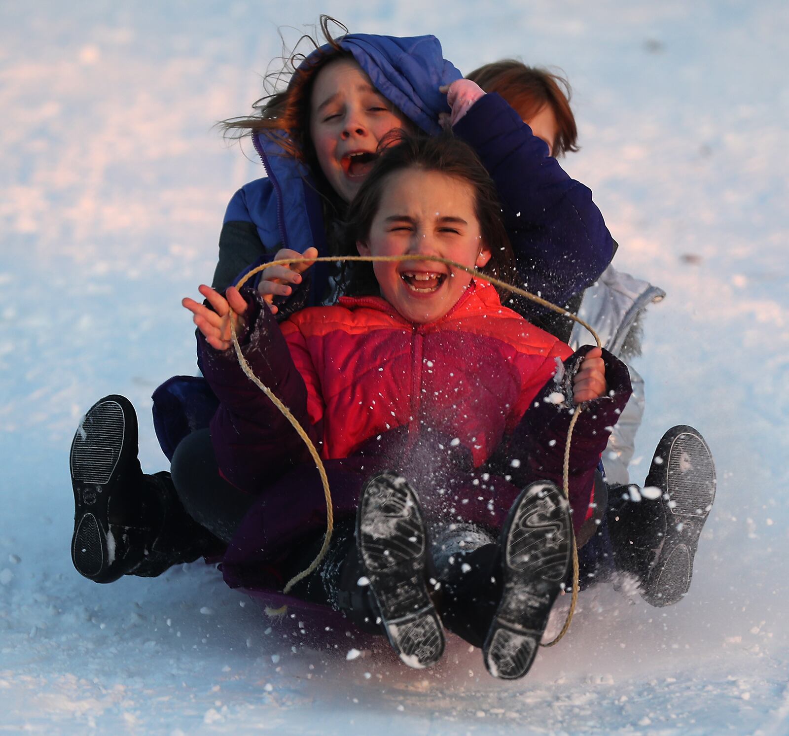 Natalya Watts, front, Alexus Watts, middle, and Mishelle Hawes scream as they sled together on the hill at Reid Park Monday evening. BILL LACKEY/STAFF