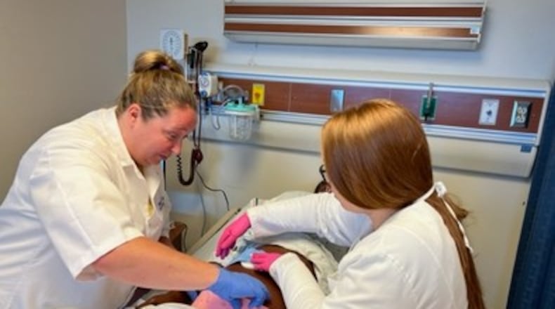 Miami Valley Career Tech Center adult division nursing students work on a dummy that helps students model a woman giving birth. Photo courtesy of MVCTC.