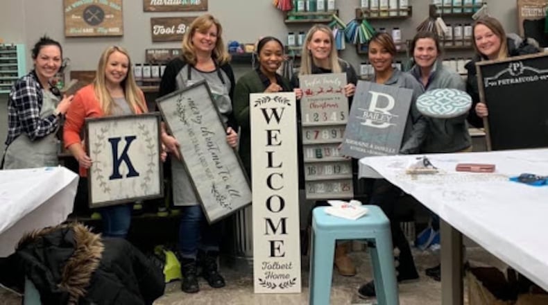 Customers hold up DIY projects that they created at an AR Workshop Centerville event.