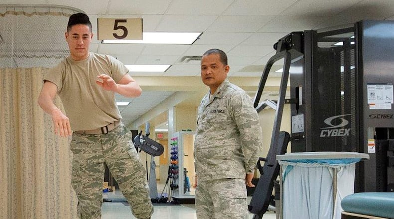 Maj. Karlo Mariano, 88th Medical Group Physical Therapy Element leader, guides Senior Airman Aaron Perry, 88th MDOS physical medicine technician on the BOSU, which works proprioception, sense of balance inside the Physical Medicine Flight, Wright-Patterson Medical Center April 8. Mariano assists clients in rehabilitation of injuries and predisposed health conditions to help clients recover faster. (U.S. Air Force photo/Michelle Gigante)