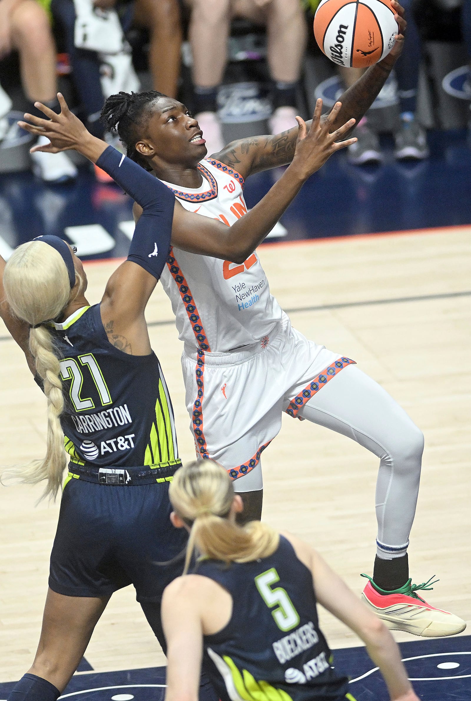 Connecticut Sun's Saniya Rivers (22) puts up a basket from under Dallas Wing's DiJonai Carrington (21) during a WNBA basketball game Tuesday, May 27, 2025, in Uncasville, Conn. (Sarah Gordon/The Day via AP)