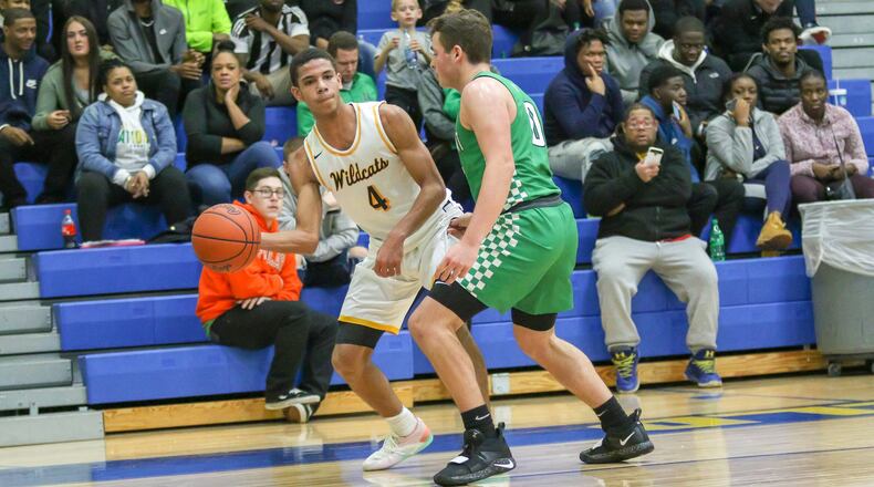 Springfield High School senior David Sanford passes the ball to a teammate against Northmont defender Miles Johnson during the Wildcats’ 78-64 victory over the Thunderbolts on Friday night in Springfield. Sanford had a team-high 21 points in the win. CONTRIBUTED PHOTO BY MICHAEL COOPER