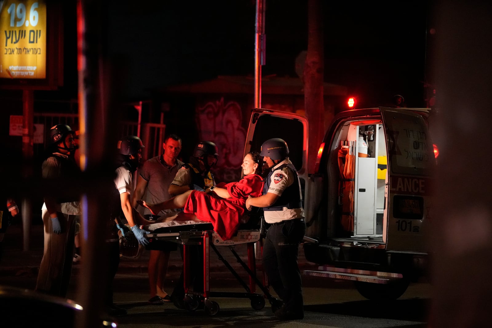Paramedics evacuate a wounded woman from a building struck by a missile fired from Iran, in Tel Aviv, Israel, on Friday, June 13, 2025. (AP Photo/Tomer Appelbaum)