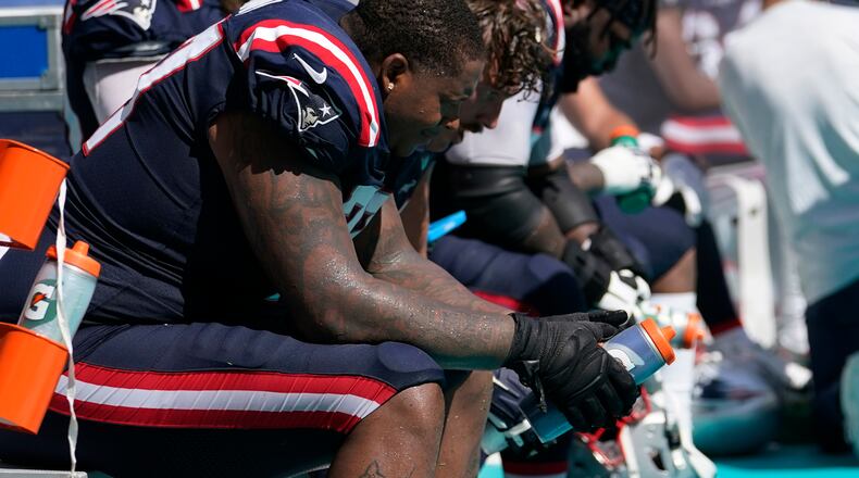 New England Patriots offensive tackle Trent Brown (77) and his teammates sit on the sidelines during the second half of an NFL football game against the Miami Dolphins, Sunday, Sept. 11, 2022, in Miami Gardens, Fla. The Dolphins defeated the Patriots 20-7. (AP Photo/Lynne Sladky)