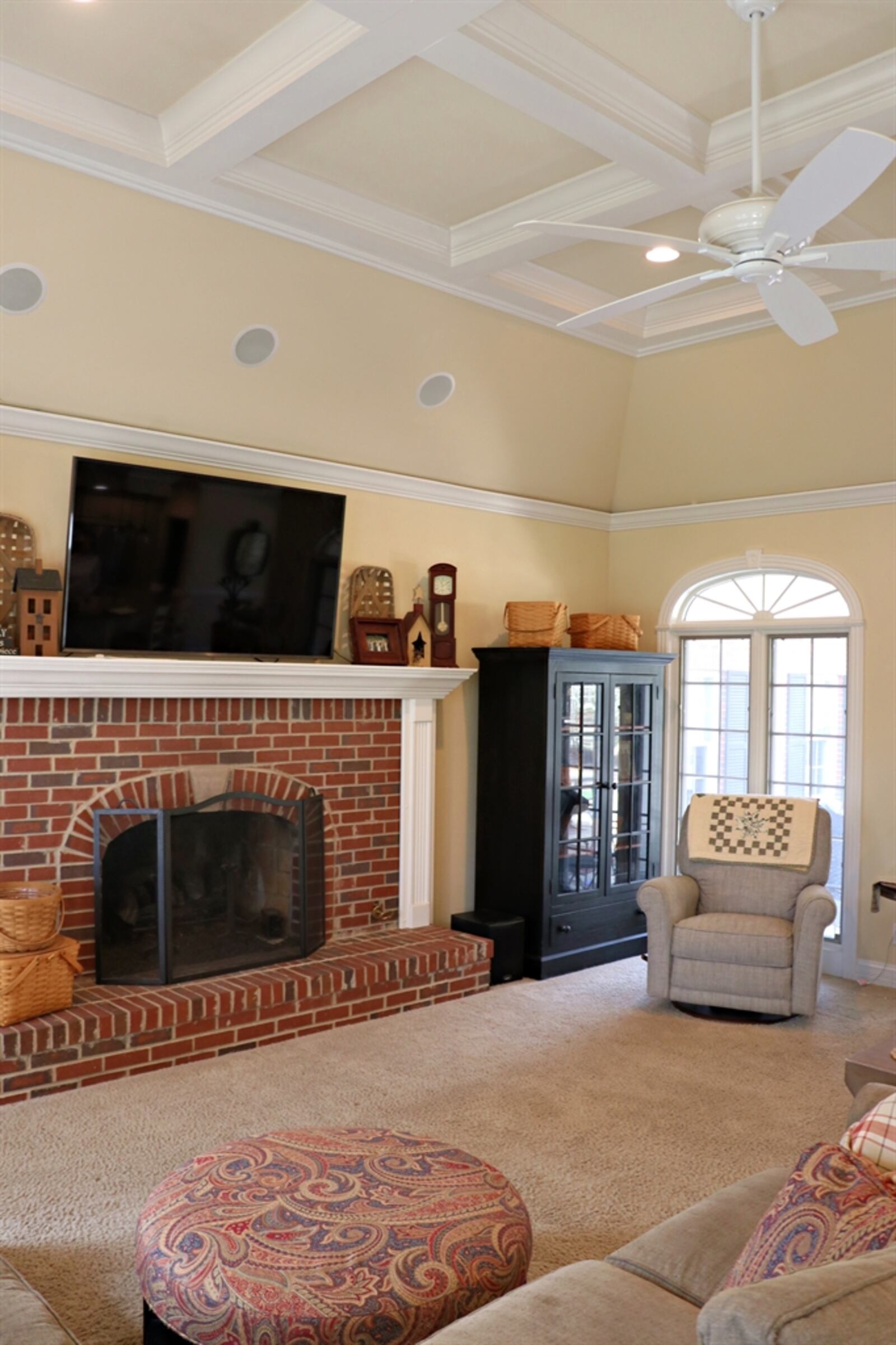 The great room includes a coffered ceiling and a large brick fireplace with wood-mantel surround and brick hearth. 