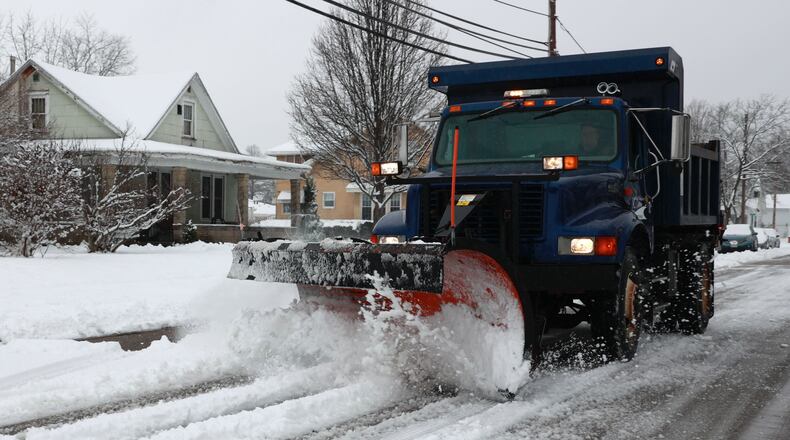 A snow plow cleans off a New Carlisle street Sunday. BILL LACKEY/STAFF