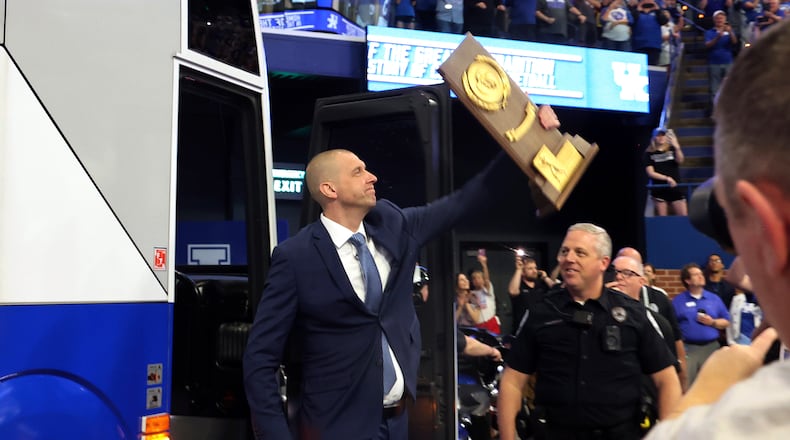 Mark Pope exits the bus he rode into the arena, carrying the 1996 Championship Trophy at an event naming him head coach of the Kentucky men's NCAA college basketball team, at Rupp Arena in Lexington, Ky., Sunday, April 14, 2024. (AP Photo/James Crisp)