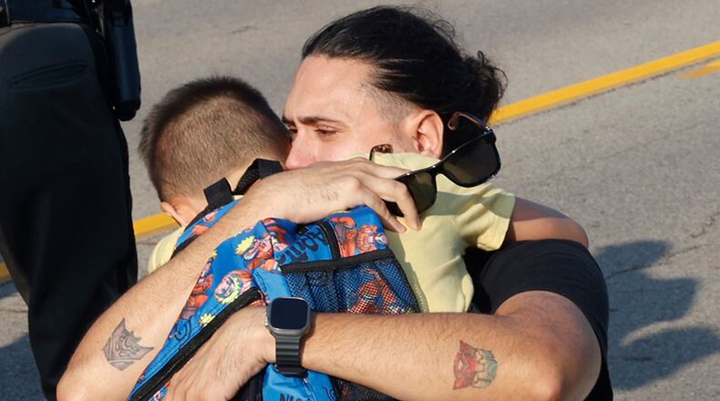 A father hugged his son at the scene of a Northwestern School District bus crash that killed one student and injured more than 20 others on State Route 41 near Springfield, Ohio Tuesday, August 22, 2023. The bus, carrying 52 elementary students on their way to the first day of school was struck by a mini van and rolled over. FILE PHOTO
