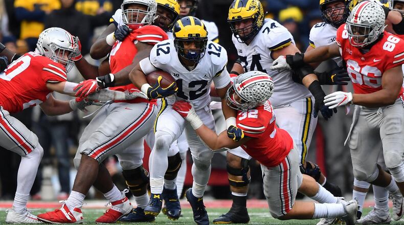 COLUMBUS, OH - NOVEMBER 24: Chris Evans #12 of the Michigan Wolverines breaks through the line as Tuf Borland #32 of the Ohio State Buckeyes drags him down in the fourth quarter at Ohio Stadium on November 24, 2018 in Columbus, Ohio. Ohio State defeated Michigan 62-39. (Photo by Jamie Sabau/Getty Images)