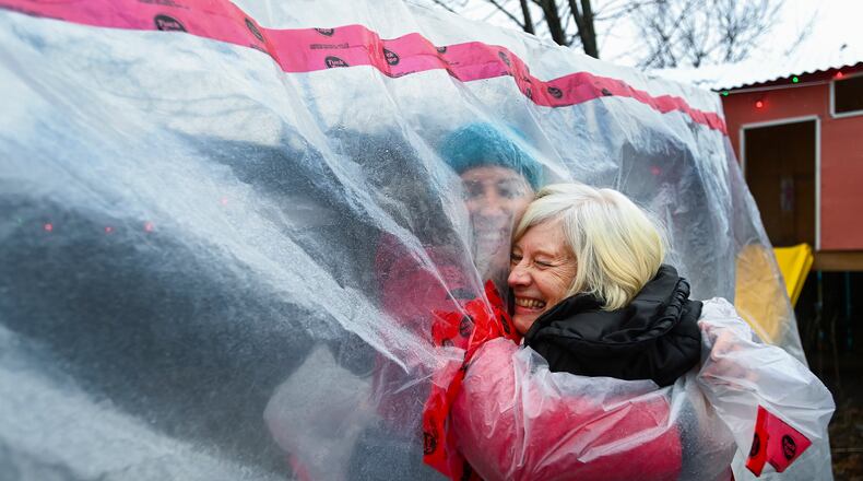 Carolyn Ellis, left, creator of the hug glove hugs her mother Susan Watts, 74, in her backyard on Christmas Eve during the COVID-19 pandemic in Guelph, Ont., Thursday, Dec. 24, 2020. Watts is a retired nurse who lives in an apartment near by and gets to come over outside and hug her daughter's family.  (Nathan Denette/The Canadian Press via AP)