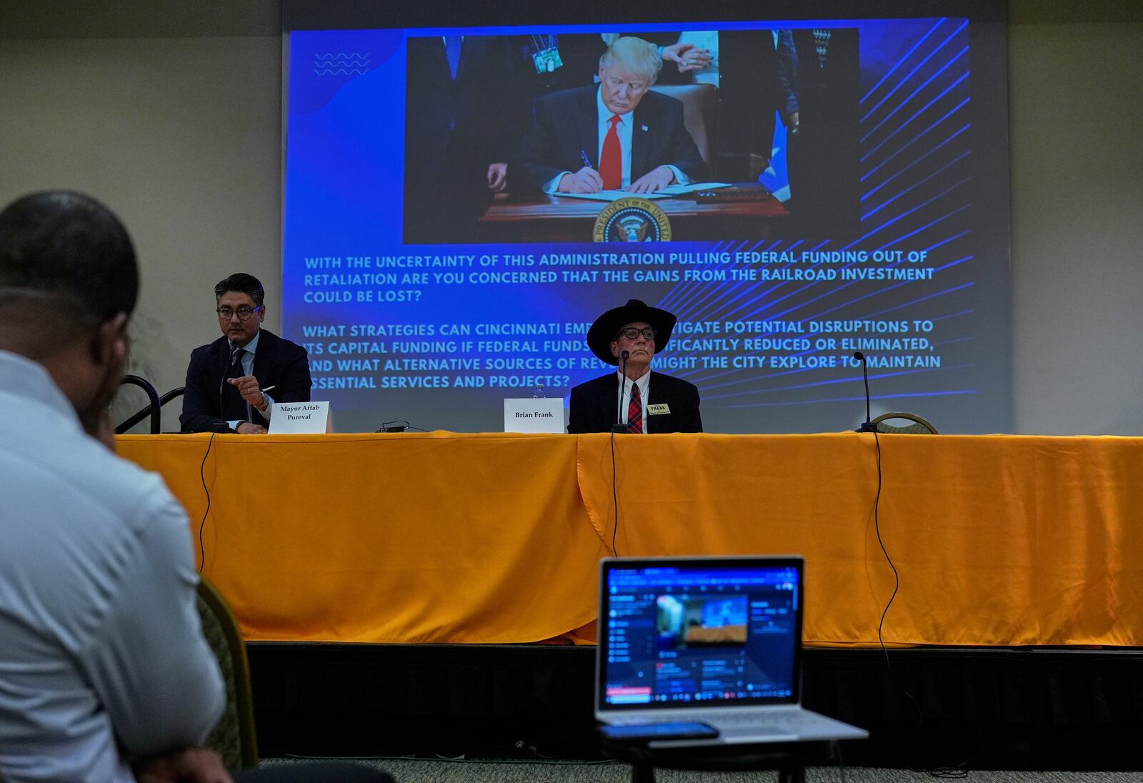 An image of President Donald Trump is displayed as incumbent Cincinnati Mayor Aftab Pureval, left, and Brian Frank participate in a candidate forum hosted by the Cincinnati NAACP, Tuesday, April 15, 2025, in Cincinnati. (AP Photo/Carolyn Kaster)