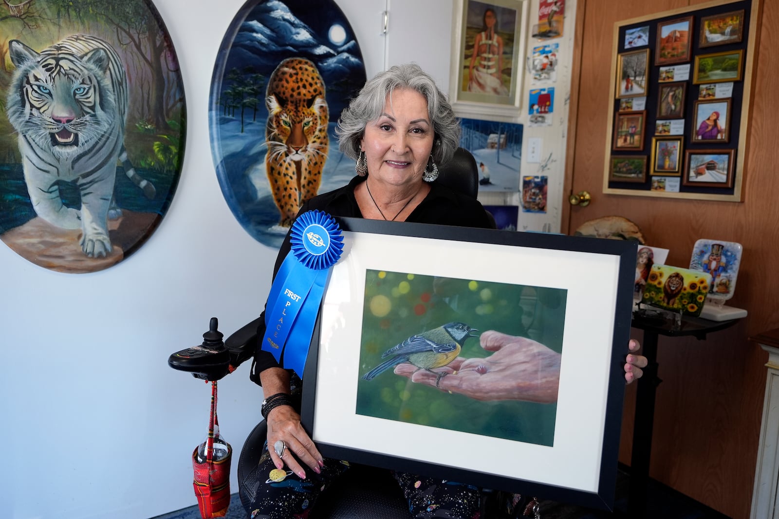 Artist Lora Duguay poses for a portrait in her wheelchair with some of her artwork at home in Clearwater, Fla., on Tuesday, June 10, 2025. (AP Photo/Chris O'Meara)