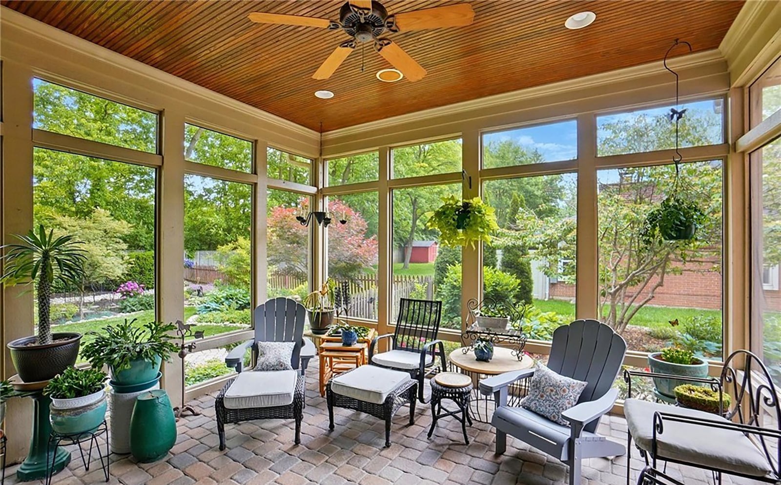 The screened in porch has a paver floor, beadboard ceiling and a fan.