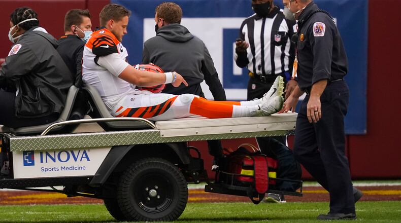 Cincinnati Bengals quarterback Joe Burrow (9) points to his knee as he is carted off the field after an injury in the second half of an NFL football game against the Washington Football Team, Sunday, Nov. 22, 2020, in Landover. (AP Photo/Andrew Harnik)