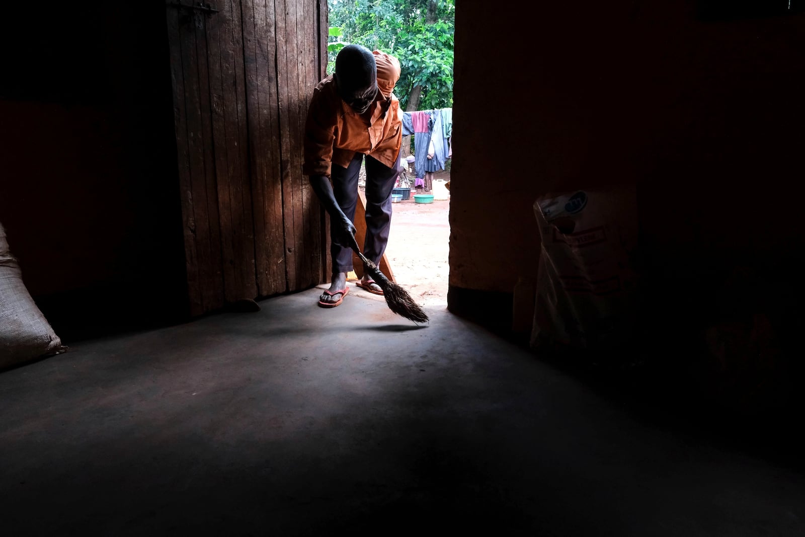 Simon Tigawalana sweeps his house with a clay-based earthen floor by EarthEnable on May 16, 2025, in Jinja, Uganda. (AP Photo/Hajarah Nalwadda)