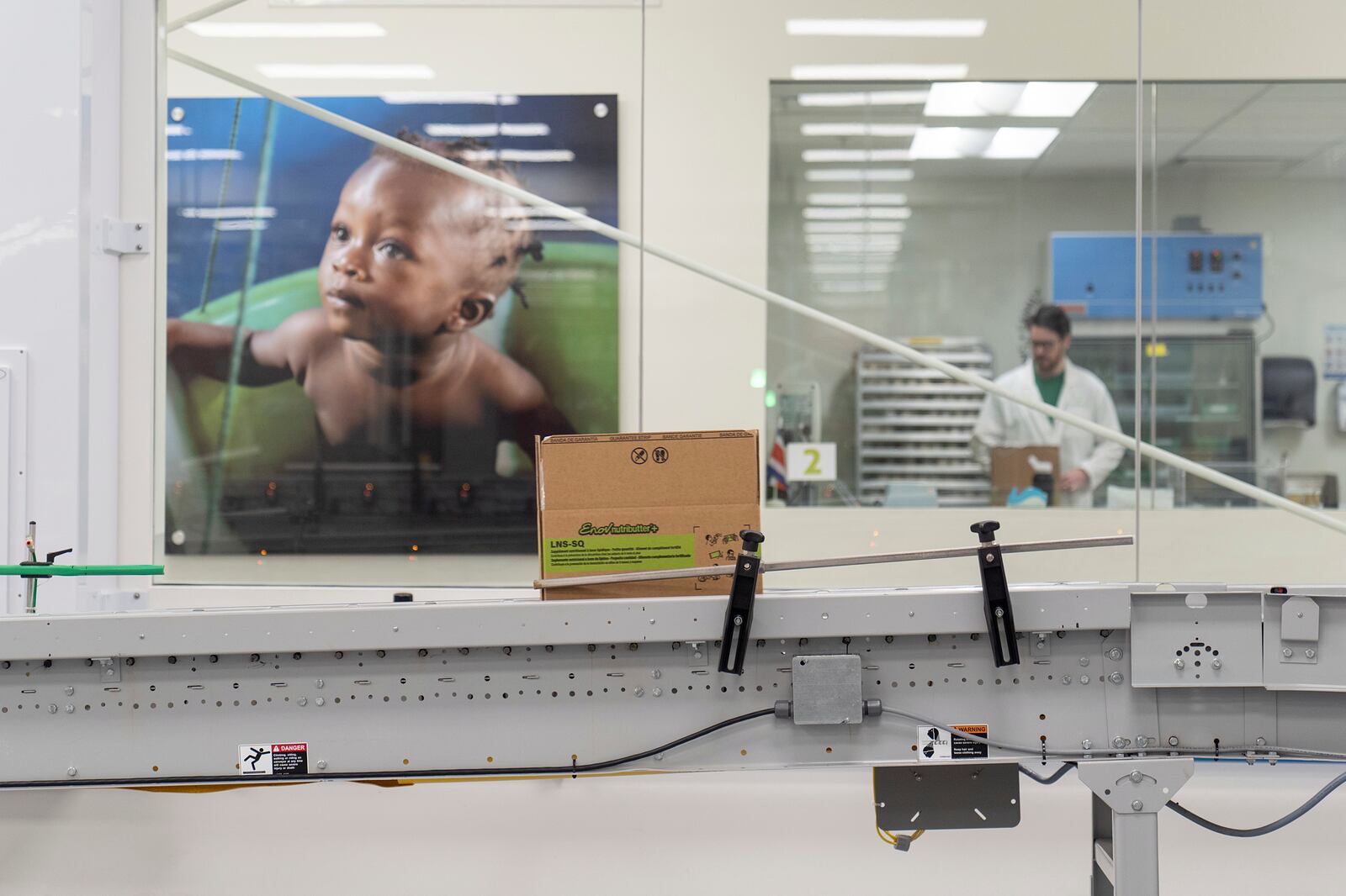 A conveyer belt usually loaded with many boxes moves a single box of Plumpy'Nut, a nutritional lifesaving peanut paste sent to malnourished children worldwide, at Edesia Nutrition, Friday, March 14, 2025, in North Kingstown, R.I. (AP Photo/David Goldman)