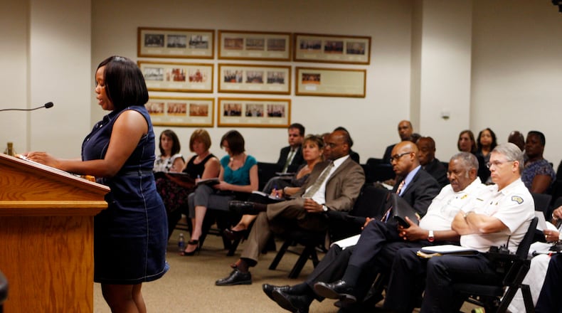 Rev. Dormetria Robinson reads a statement, with Director and Chief of Dayton Police Richard Biehl and Dayton Fire Chief Herbert C Redden II sitting in the audience, from a coalition of community leaders and clergy that reflects on the Kylen English situation and that deals with the tension of the community to the Dayton City Commission during their meeting on Wednesday, August 3.