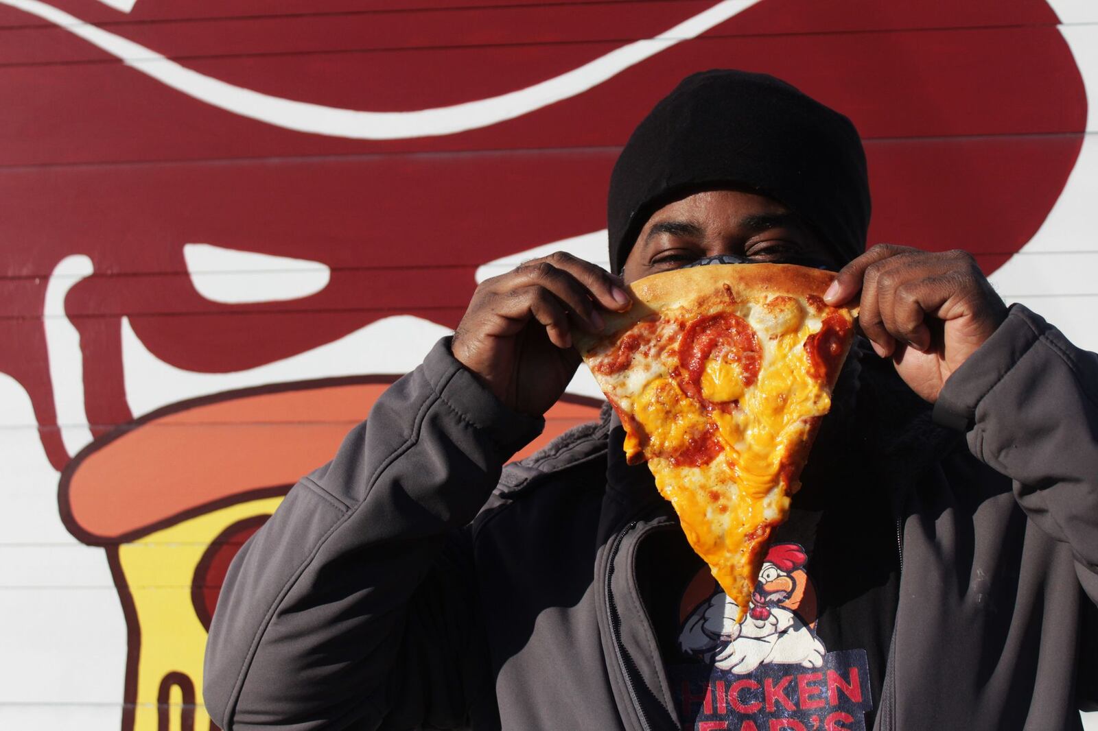 Chef Anthony Head, owner of Chicken Head's restaurant, poses with a slice of pizza from Pizza Bandit, which has added Chicken Head's mac 'n' cheese sauce as a topping option as part of a collaboration between the two businesses. CONTRIBUTED