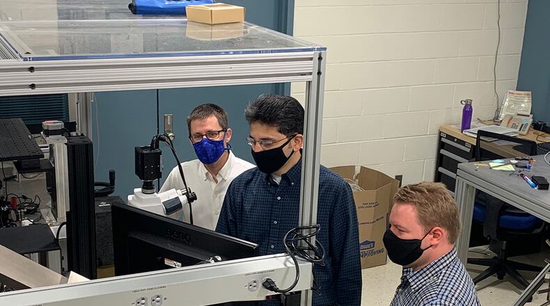 From left to right: Dr. Derek Bas, Dr. Piyush Shah and Dr. Michael Page examine a potential acoustically driven ferromagnetic resonance material under a microscope in the magneto-optics lab. The microscope is designed to observe magnetic properties on a small scale. (U.S. Air Force photo/Michael Wolf)