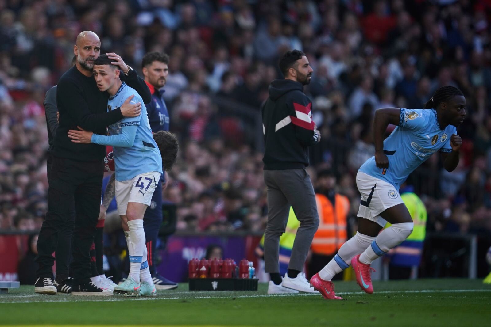 Manchester City's head coach Pep Guardiola hugs Phil Foden as he is substituted during the English Premier League soccer match between Manchester City and Manchester United in Manchester, England, Sunday, April 6, 2025. (AP Photo/Dave Thompson)