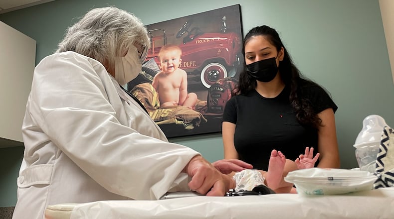 File - Dr. Sara Goza explains an infant's upcoming vaccinations to his mother in an exam room at First Georgia Physician Group Pediatrics in Fayetteville, Ga., Tuesday, Aug. 17, 2021. (AP Photo/Angie Wang)