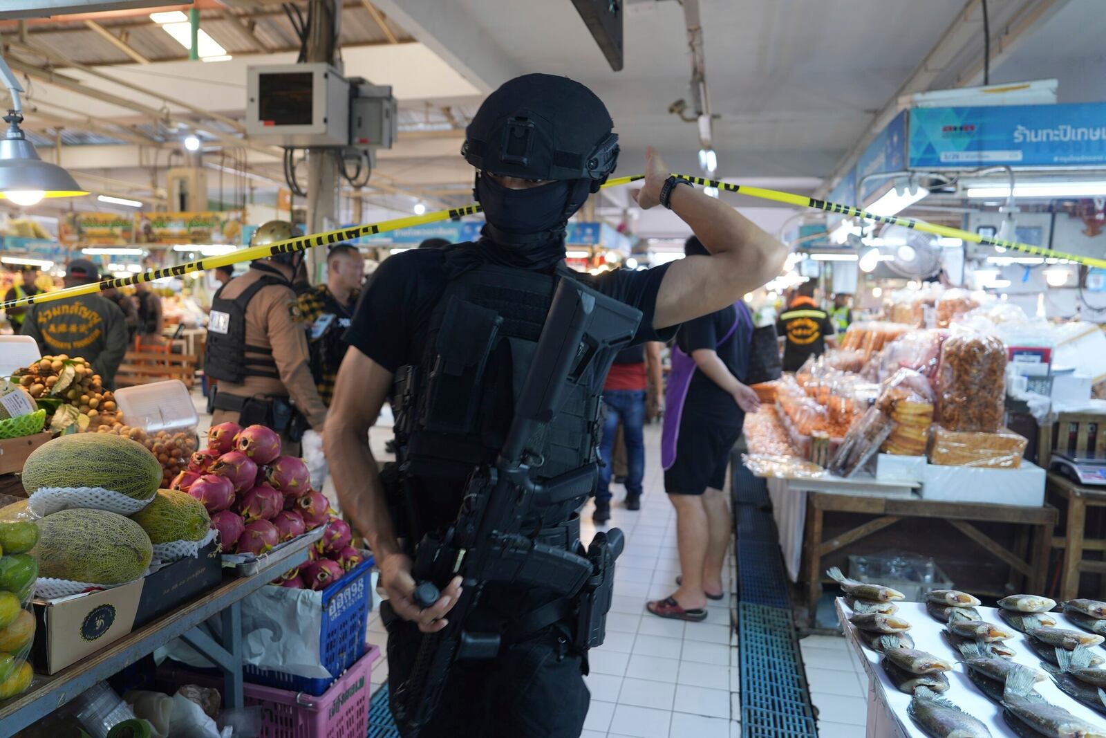 A policeman of a special operations unit at a crime scene at a market in Bangkok, Thailand, Monday, July 28, 2025 where police says six people are dead after a shooting incident. (AP Photo/Nava Sangthong)