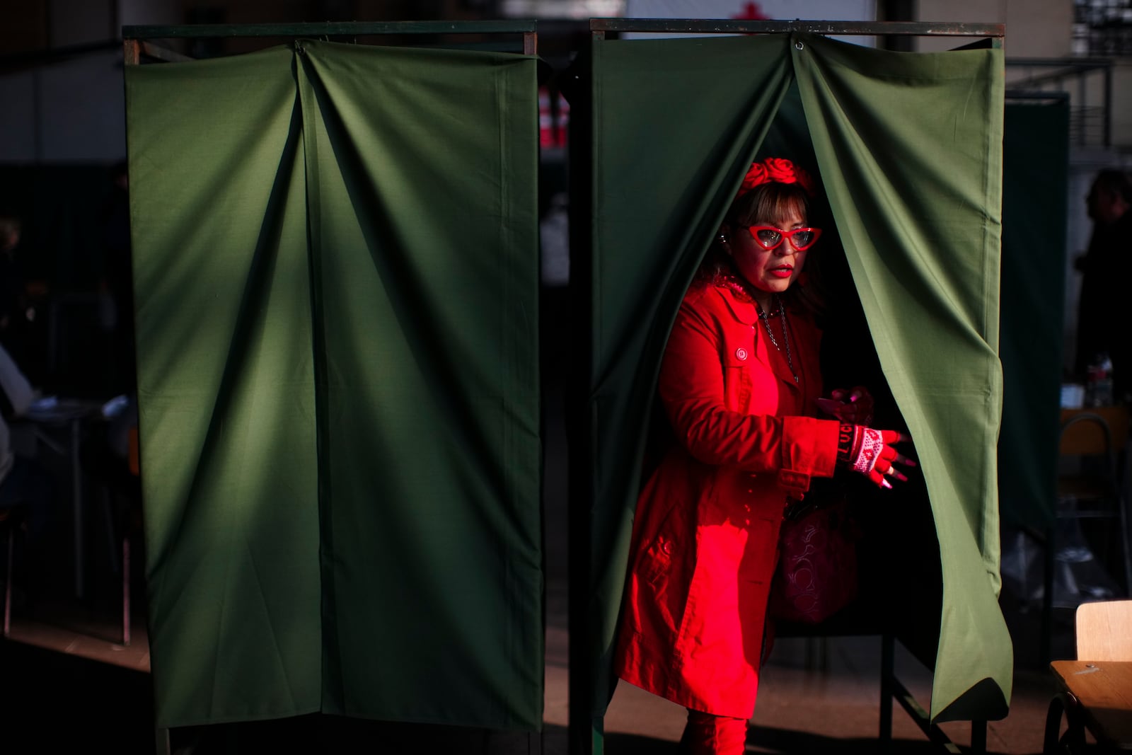 A voter leaves a booth after casting her ballot in primary elections held by the Unidad por Chile coalition to choose the ruling party's candidate for the upcoming presidential election, in Santiago, Chile, Sunday, June 29, 2025. (AP Photo/Esteban Felix)