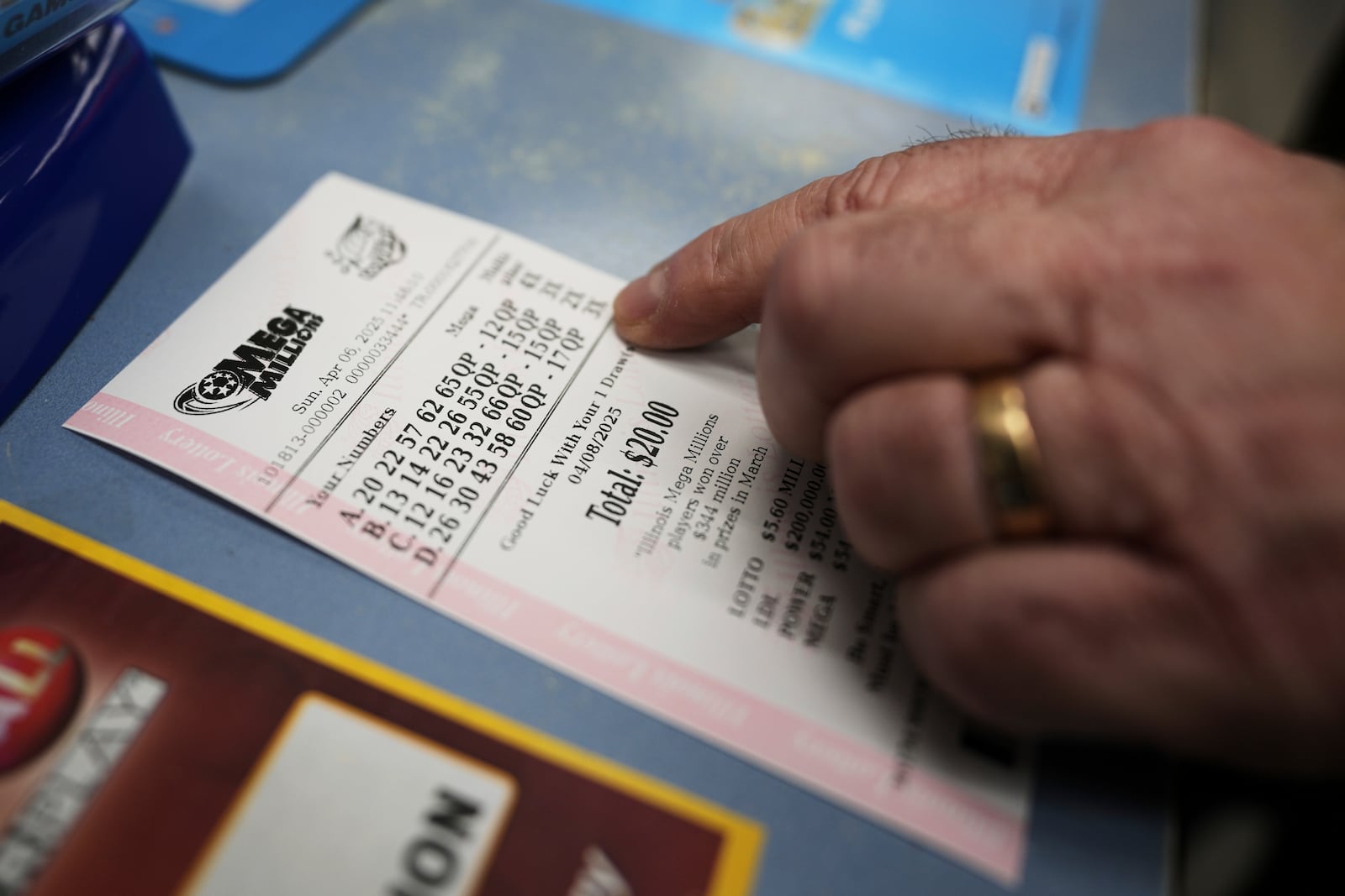 Pete Gruber points a Mega Millions lottery ticket after he purchased at Mares Mart in Chicago, Sunday, April 6, 2025. (AP Photo/Nam Y. Huh)