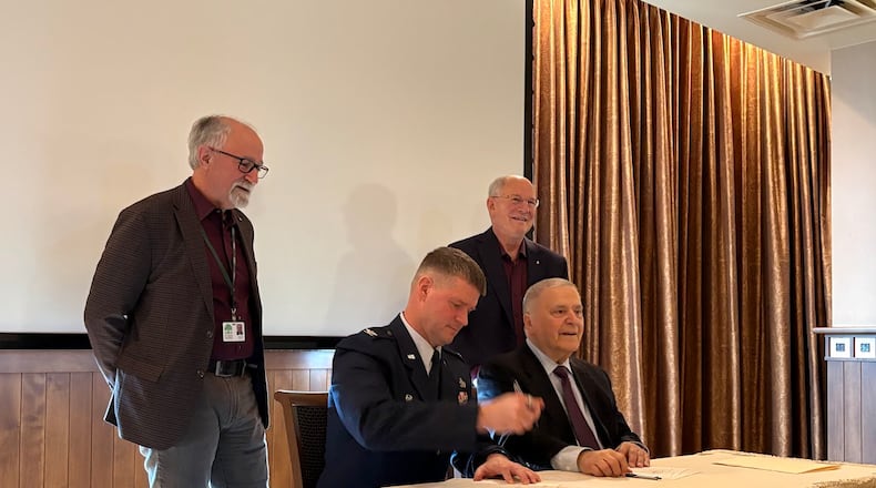 An outgrant license is signed Tuesday, Feb. 17, 2026 for work leading to what advocates hope will be a new STEM Talent Development Complex near the National Museum of the U.S. Air Force. Standing are (left) Joe Sciabica, who leaders the Employers Workforce Coalition, and retired Air Force Lt. Gen. Dick Reynolds, co-founder of Air Camp. Seated are (left) Col. Dustin Richards, 88th Air Base Wing commander and Vince Russo, Air Camp co-founder. THOMAS GNAU/STAFF