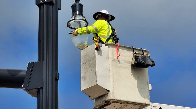 Hamilton utility employee Adam Wong works on a light post on Monday, March 4, 2024, at the intersection of High Street and MLK Jr. Boulevard. Hamilton City Council is considering decreasing electric rates and increasing natural gas rates. NICK GRAHAM/STAFF
