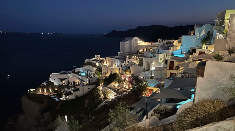 The blue lights of infinity pools and jacuzzis of luxurious hotels illuminate the village of Oia, on the island of Santorini, Greece, on Sept. 3, 2021. Oia is the ritziest of the villages carved into the rim of the island volcano that exploded into the sea 3,600 years ago. (AP Photo/Giovanna Dell’Orto)