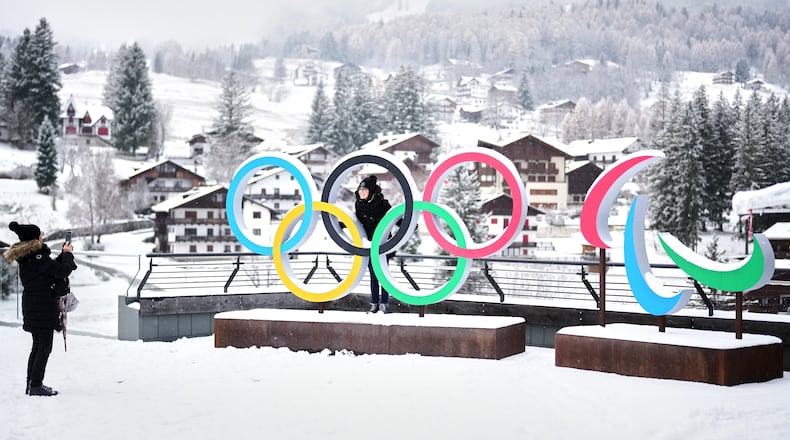 FILE - People take photos in front of the Milan Cortina Winter Olympics and Paralympics rings, in Cortina D'Ampezzo, on Nov. 20, 2025. (AP Photo/Andrew Medichini, File)