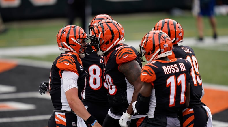 Cincinnati Bengals quarterback Joe Burrow, left, celebrates with teammates after Burrow ran for a touchdown during the first half of an NFL football game against the Los Angeles Chargers, Sunday, Sept. 13, 2020, in Cincinnati. (AP Photo/Bryan Woolston)