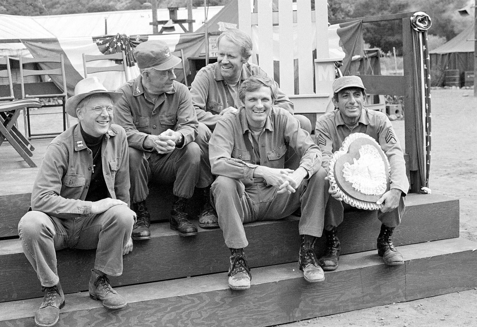 FILE - Cast members of the television series "M*A*S*H," from left, William Christopher, Harry Morgan, Mike Farrell, Alan Alda, and Jamie Farr, appear on the set during taping in Los Angeles on Sept. 15, 1982. (AP Photo/Wally Fong, File)