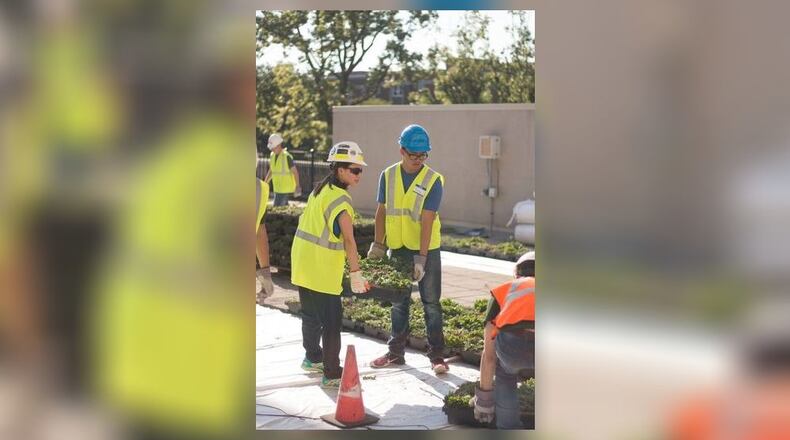 University of Dayton students Megan Zaratzian and Josh Romo help with the installation of the Kennedy Union Rooftop Garden during the first week of September. CONTRIBUTED