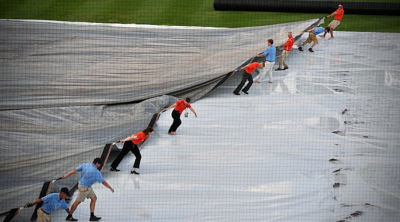 Ground crews remove the tarp from the field at Day Air Ballpark after a heavy rainfall Friday, Aug. 20, 2021, moved through downtown Dayton. MARSHALL GORBY\STAFF