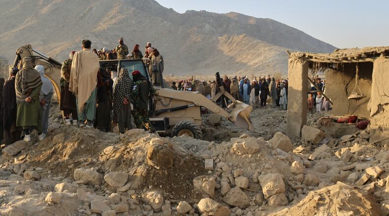Local residents and civil defense workers look on as a bulldozer clears the rubble of a house hit by a cross-border Pakistani army strike in the Behsud district of Nangarhar province, Afghanistan, Sunday, Feb. 22, 2026. (AP Photo/Hedayat Shah)