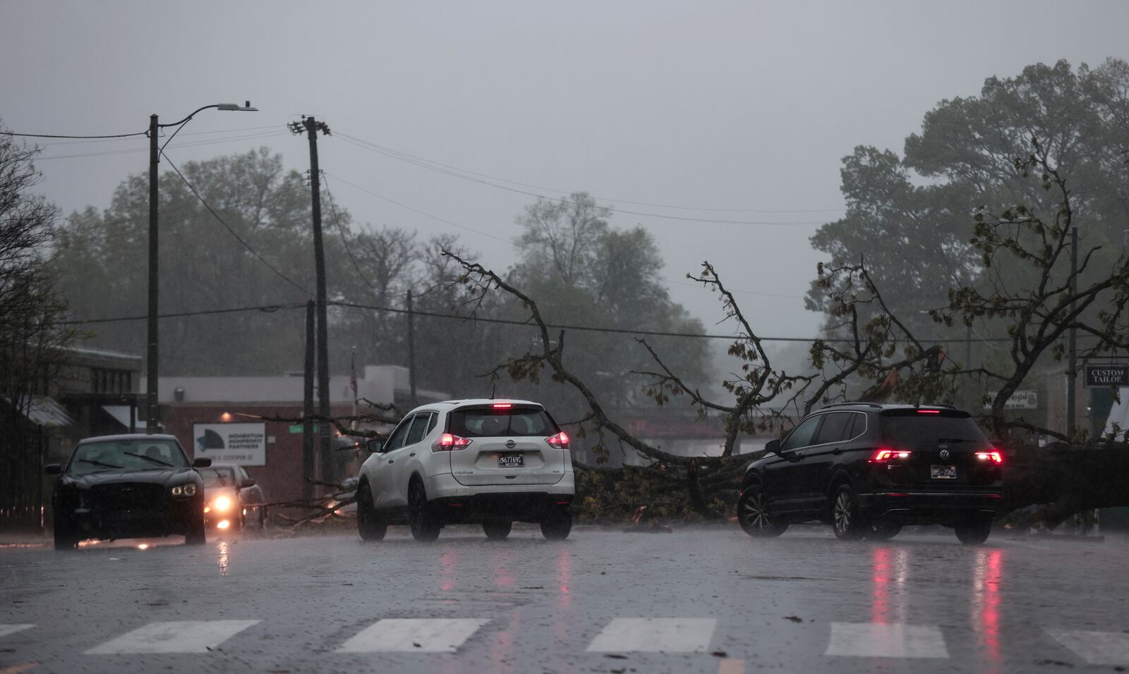 Vehicles go around a downed tree on Cooper Street as heavy rain falls, Saturday, April 5, 2025, in Memphis, Tenn. (Patrick Lantrip/Daily Memphian via AP)