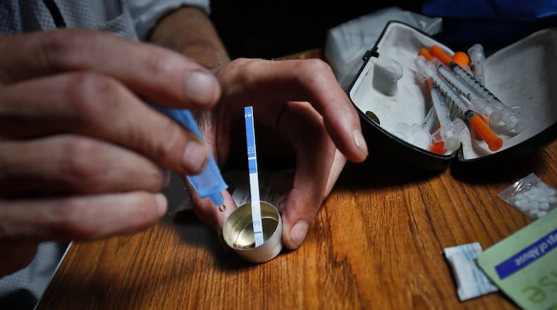 An addict prepares heroin, placing a fentanyl test strip into the mixing container to check for contamination. FILE PHOTO