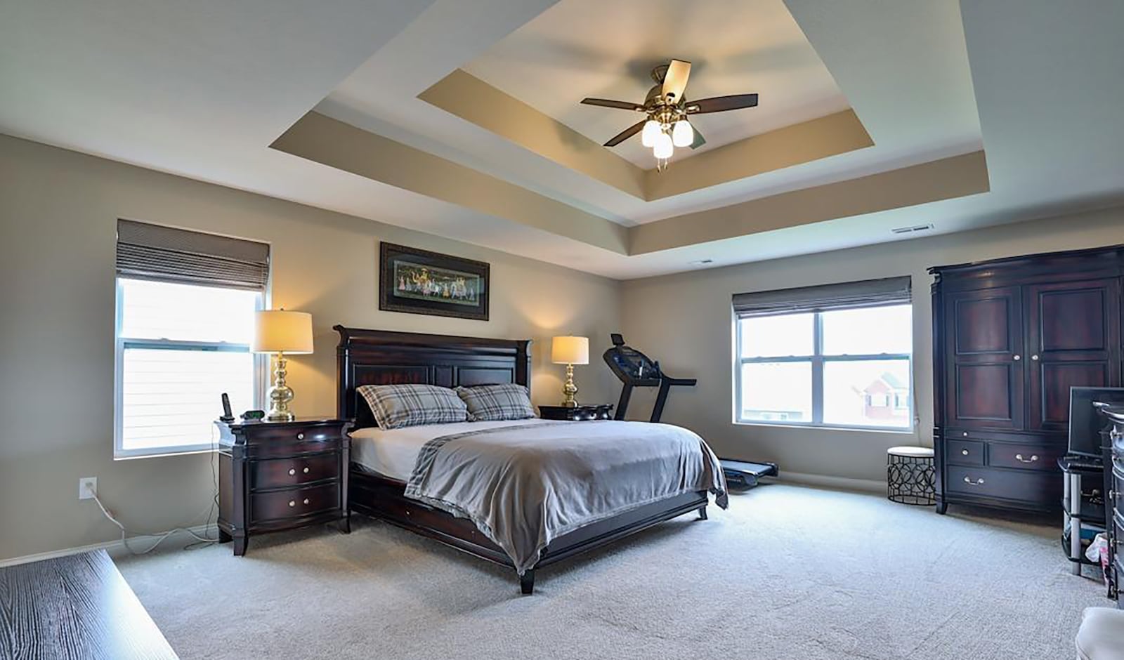 The primary bedroom suite has carpeting, a tray ceiling and ceiling fan and an ensuite bathroom