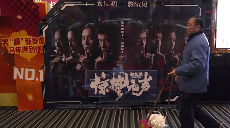 A cleaner walks past a promotion board for "Scare Out" at a cinema in Beijing, Saturday, March 7, 2026. (AP Photo/Ng Han Guan)
