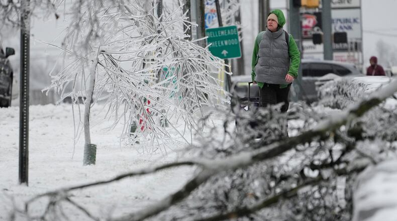A person walks past ice covered trees and a fallen limb during a winter storm Sunday, Jan. 25, 2026, in Nashville, Tenn. (AP Photo/George Walker IV)