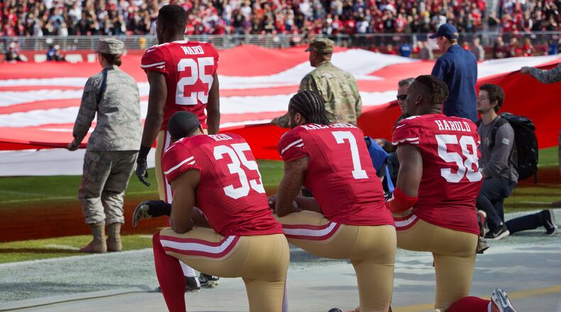 SANTA CLARA, CA - NOVEMBER 6: Quarterback Colin Kaepernick #7, safety Eric Reid #35, and linebacker Eli Harold #58 of the San Francisco 49ers kneel before a game against the New Orleans Saints with the U.S. flag unfurled in honor of the armed services on November, 6 2016 at Levi's Stadium in Santa Clara, California. The Saints won 41-23. (Photo by Brian Bahr/Getty Images)