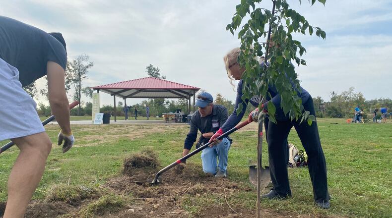 Volunteers Andrew Schulte, left, works with Tim Bement and Ami Bement, right, to plant a tree Saturday at Sinclair Park in Harrison Township. Eileen McClory / Staff