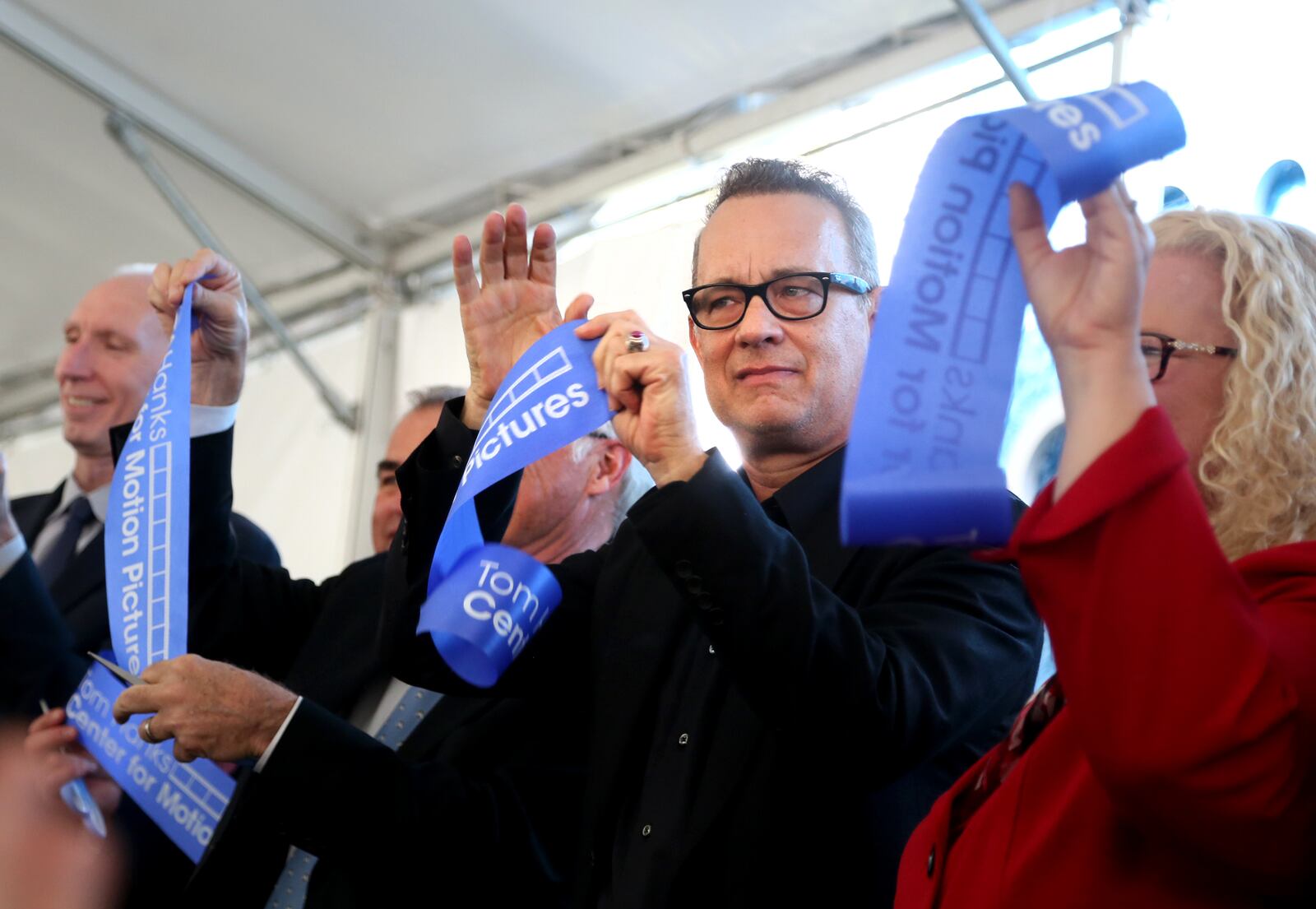 Actor Tom Hanks holds up a piece of cut ribbon after participating in a ribbon cutting for the new Tom Hanks Center for Motion Pictures at Wright State University Tuesday. LISA POWELL / STAFF
