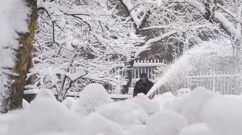 A groundskeeper clears snow from the walkways inside the Trinity Church graveyard in lower Manhattan during a snow storm, Monday, Feb. 23, 2026, in New York. (AP Photo/Seth Wenig)